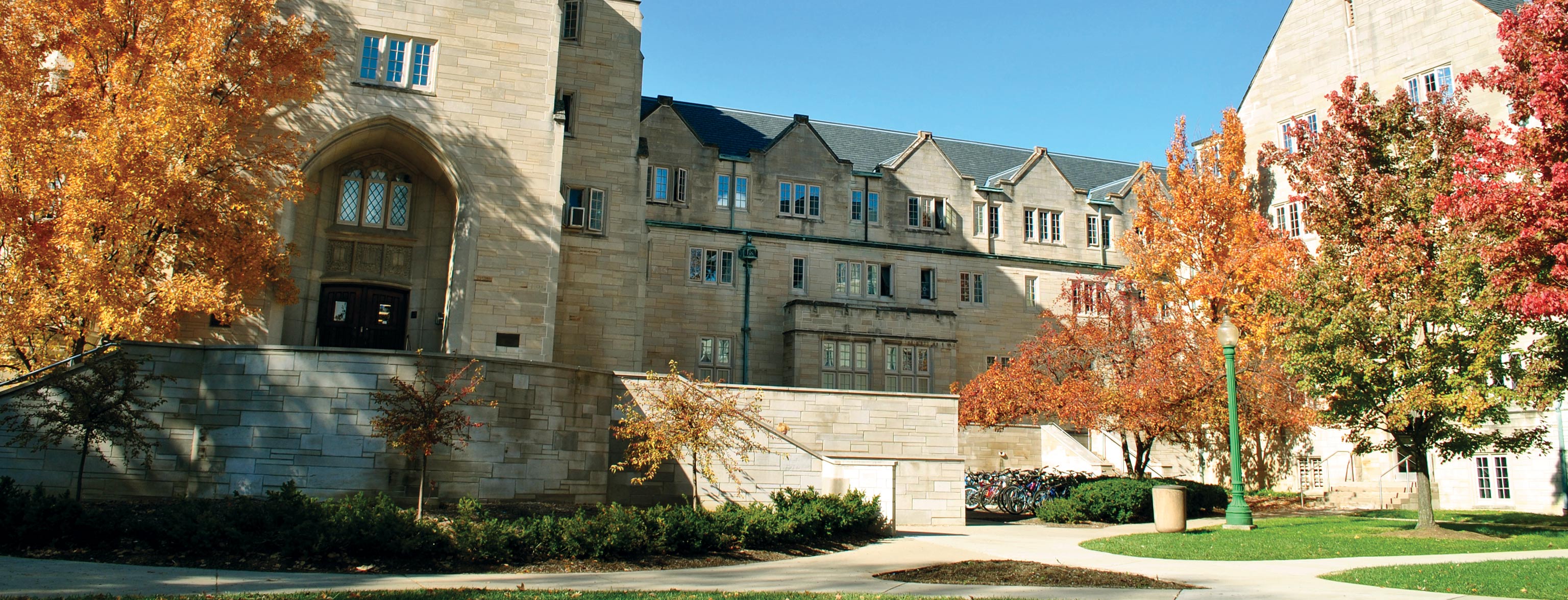 The exterior of Collins Living-Learning Center in the fall when the leaves on its courtyard trees are red. orange, and green