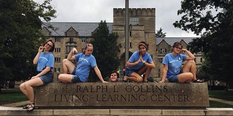 Five students posing with the Collins Living-Learning Center sign